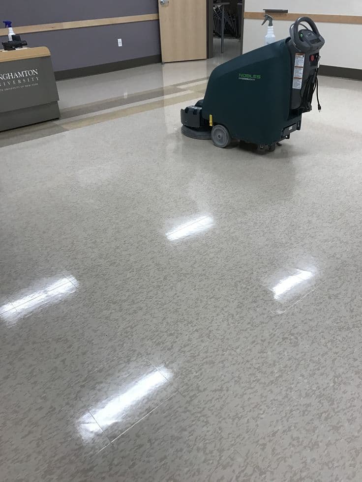 Lavadora automática trabalhando em área interna com piso brilhante.